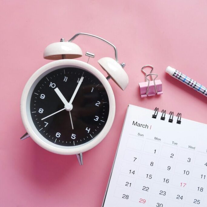 clock next to pen and calendar for scheduling