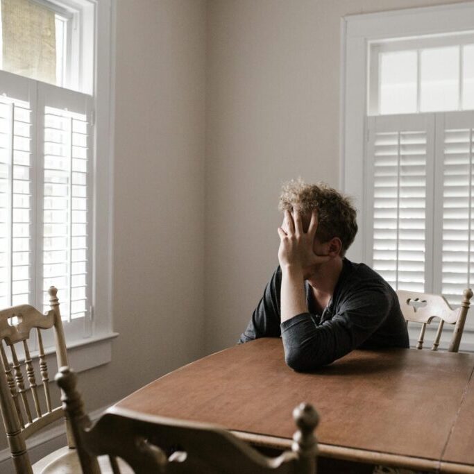 young adult at a kitchen table who feels confused