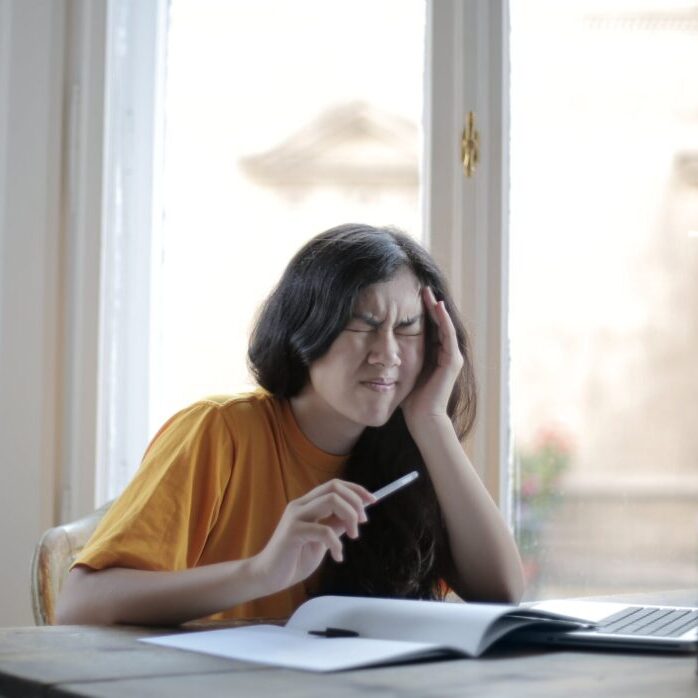 female sitting down at desk struggling with work