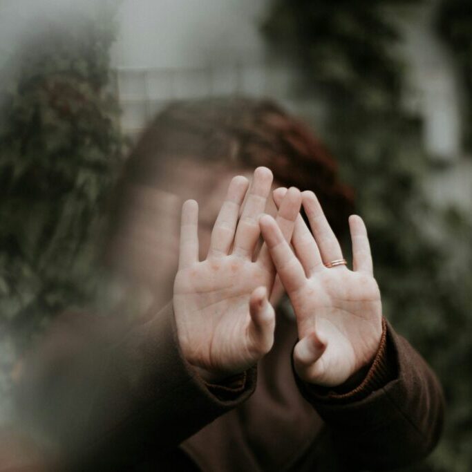 person blocking their face with both of their hands