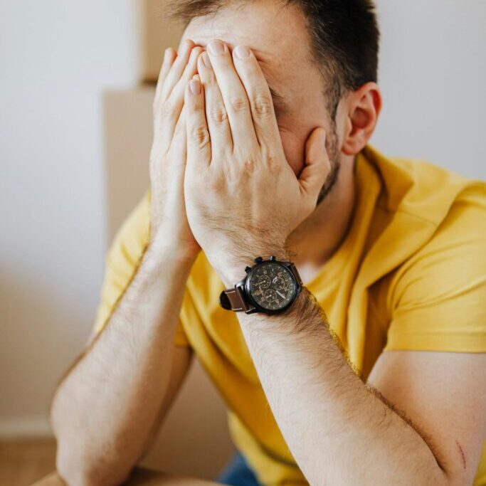 person covering up their facial expression with hands